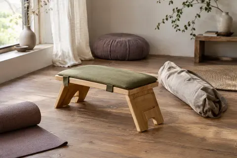 Banc de méditation pliant en bambou avec coussin vert et sac de transport dans un intérieur calme