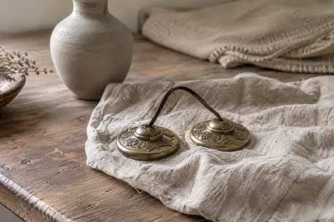Paire de cymbales Tingsha en métal bronze posée sur du lin dans un intérieur calme