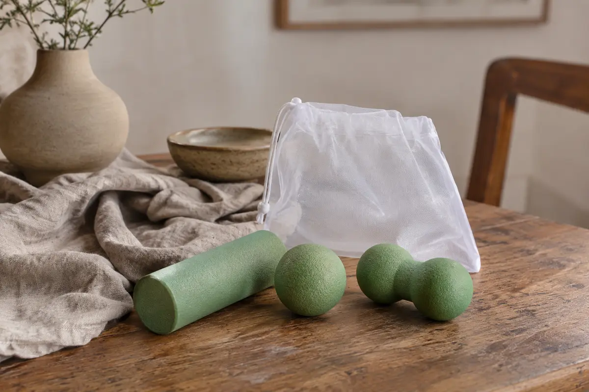 Kit vert de massage avec mini rouleau, balle simple et balle double disposés sur un linge clair