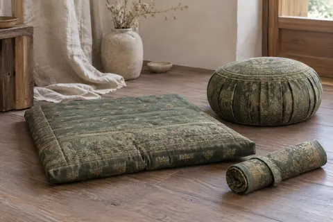 Ensemble zafu et zabuton vert à motifs thaïs, posé sur un sol en bois dans un intérieur calme.
