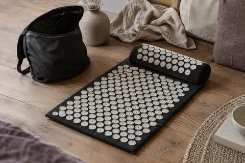 Tapis d’acupression noir et blanc avec oreiller et sac de rangement dans un intérieur calme