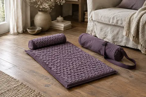 Tapis d’acupression violet avec oreiller assorti et sac de transport posé dans un intérieur calme