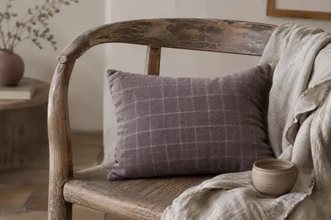 Bouillotte sèche rectangulaire en coton à motif quadrillé, posée sur un fauteuil dans un intérieur calme.