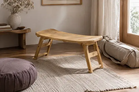 Banc de méditation pliable en bambou posé près d’un tapis et de son sac de transport