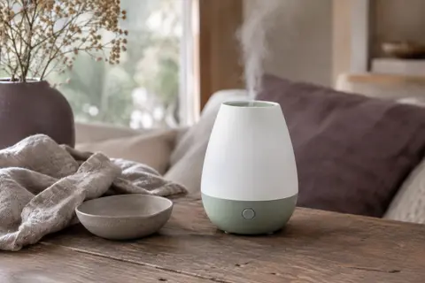 Diffuseur ultrasonique blanc et vert posé sur une table en bois dans un intérieur calme