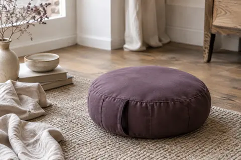 Coussin rond de méditation en coton couleur mûrier, posé sur un tapis dans un intérieur calme.