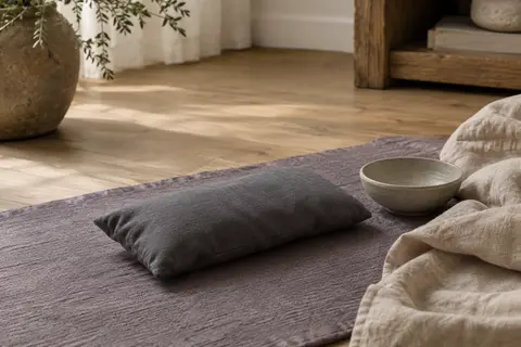 Coussin pour les yeux gris graphite en coton, posé sur un textile de lin dans un intérieur calme